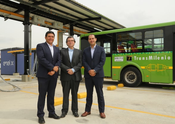 Three men posing by an electric bus