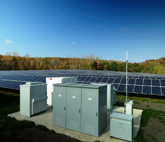 Photo of a field with solar panels and energy storage 