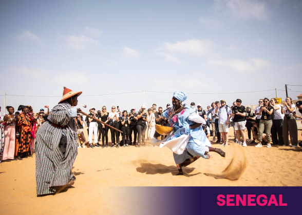 Senegalese women dancing on a beach, surrounded by spectators