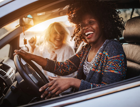 Due donne sorridenti a bordo di un'automobile
